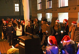 Chor der PMS mit Weihnachtsmützen und Lichtern in der Hand im Innenhof der PHSt